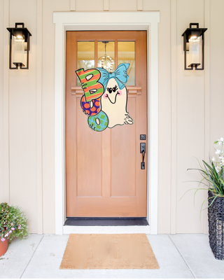 Decorative door hanger with colorful letters on a wooden front door.