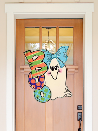 Decorative door hanger with a ghost and colorful letters on a wooden door.