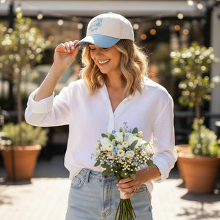 Woman holding flowers and adjusting a cap outdoors