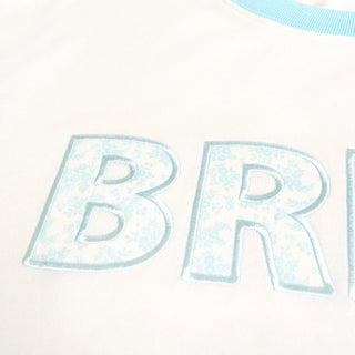 Partial view of a shirt with 'BR' printed on it, featuring a light blue and white color scheme.