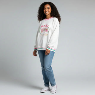 Woman wearing a white sweatshirt with colorful text and blue jeans on a gray background