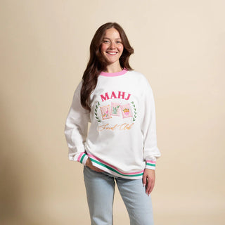 Woman wearing a white sweatshirt with colorful text and graphics on a beige background