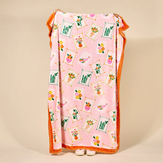 Pink blanket with floral and geometric pattern on a beige background