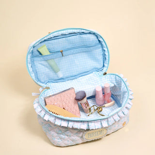 Open blue cosmetic bag with vanity items on a beige background