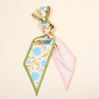 Two floral scarves, one green and blue patterned and the other pink, on a beige background.