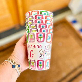 Colorful cup with game-themed design held by a hand, blurred background