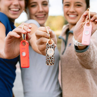 Three people holding up colorful keychains in a casual outdoor setting