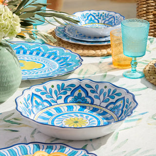 Decorative table setting with blue and white patterned plates and glasses on a floral tablecloth.