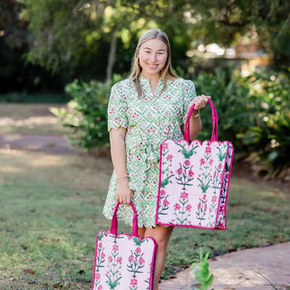 Woman in a green dress holding two floral bags outdoors.