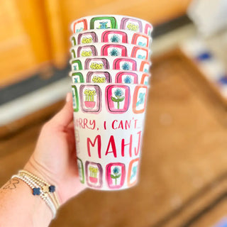 Colorful tumbler with patterned design held by a hand, blurred background