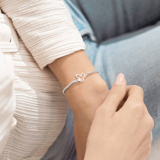 Close-up of a wrist wearing a silver bracelet with heart design.