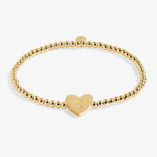 Gold bracelet with a heart-shaped tag on a white background