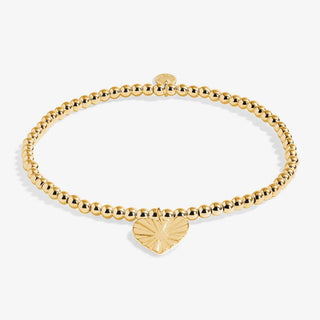 Gold beaded bracelet with a heart-shaped charm on a white background