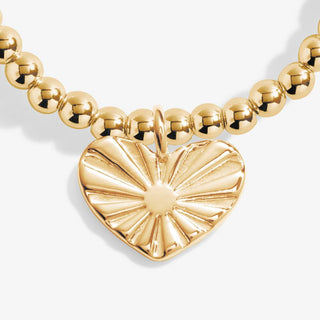 Gold necklace with a heart-shaped pendant on a white background