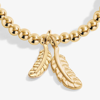 Gold beaded necklace with feather charm on a white background