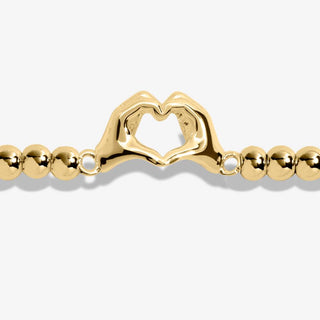 Gold bracelet with a heart-shaped clasp on a white background