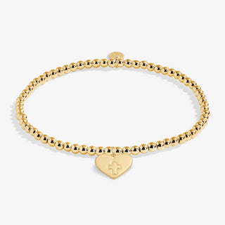 Gold bracelet with a heart-shaped tag featuring a cross on a white background