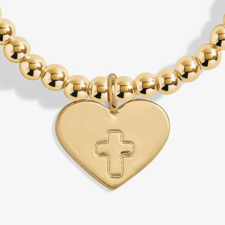 Gold beaded bracelet with a heart-shaped charm featuring a cross on a white background