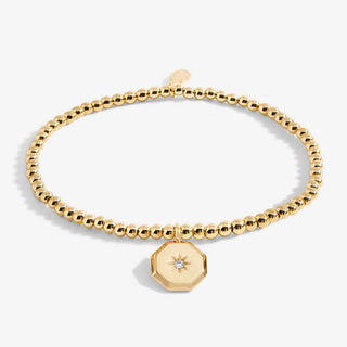 Gold beaded bracelet with a hexagonal charm on a white background