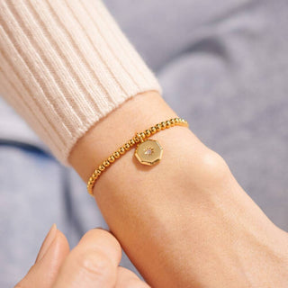 Gold bracelet on a wrist with a blurred background