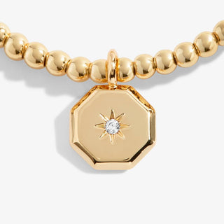 Gold beaded bracelet with a hexagonal pendant featuring a star design on a white background