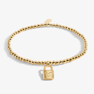 Gold beaded bracelet with a lock charm on a white background