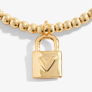 Gold beaded bracelet with a padlock charm on a white background