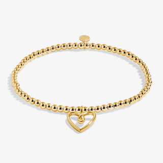 Gold bracelet with a heart-shaped charm on a white background