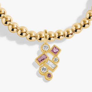 Gold bracelet with a star-shaped charm featuring pink and clear gemstones on a white background