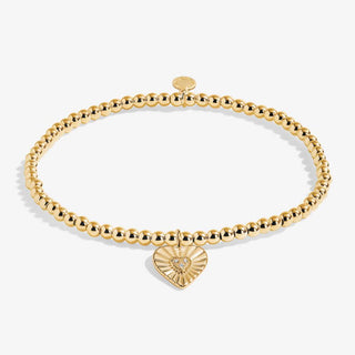 Gold bracelet with a heart-shaped charm on a white background