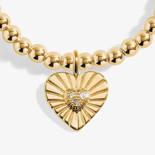 Gold beaded necklace with a heart-shaped pendant on a white background