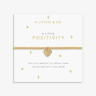 Gold bracelet with heart charm on a branded card