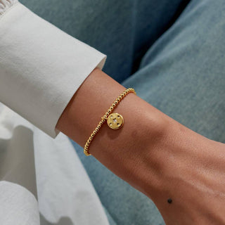 Gold bracelet on a wrist with a blurred background