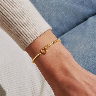 Gold bracelet on a wrist with a neutral background