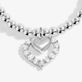 Silver bracelet with a heart-shaped clasp and clear gemstones on a white background