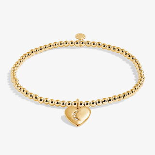 Gold bracelet with a heart-shaped charm on a white background