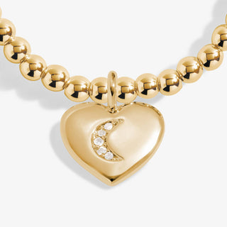 Gold bracelet with a heart-shaped pendant on a white background