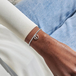 Silver bracelet on a wrist with a neutral background