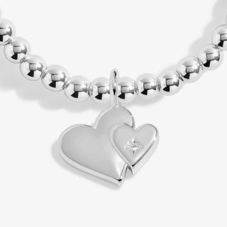 Silver beaded bracelet with a heart-shaped charm featuring a diamond on a white background