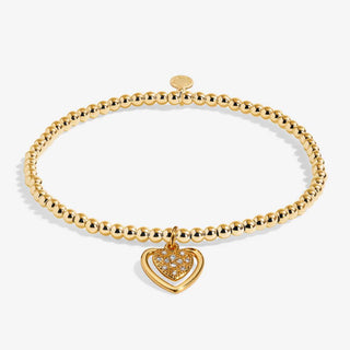 Gold bracelet with a heart-shaped charm on a white background