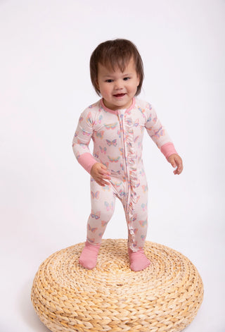 Child wearing a pink butterfly-patterned onesie on a white background