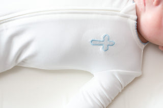 Close-up of a baby's onesie with a blue cross design on a white background