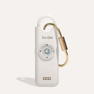 White handheld device with gold carabiner on a light gray background