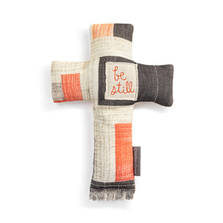 Textile cross with 'be still' text on a white background