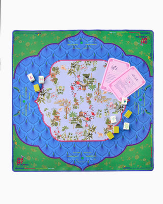 Board game setup with colorful board, cards, and dice on a decorative mat.