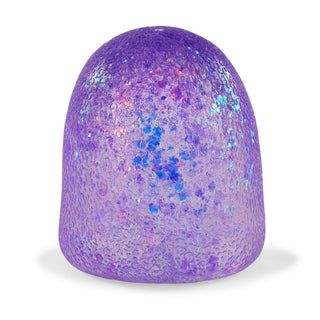 A dome-shaped textured silicone or rubber object in iridescent purple with blue, pink, and lavender holographic glitter, shown on a white background.