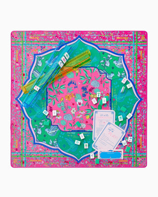 Colorful game board with dice and cards on a pink and green patterned background