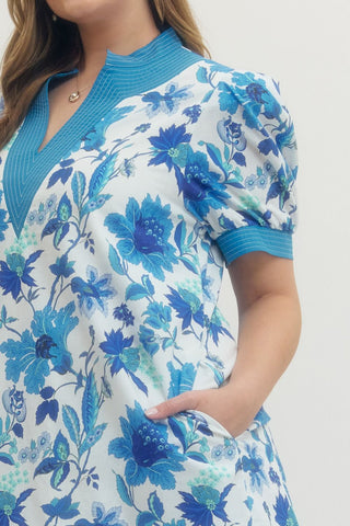 Woman wearing a blue floral dress with a white background