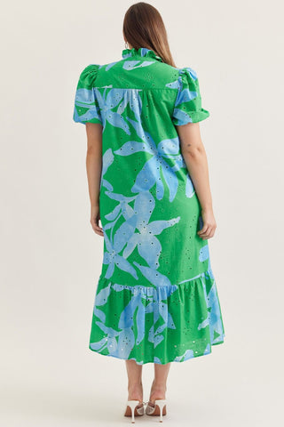Woman wearing a green dress with blue floral pattern on a plain background
