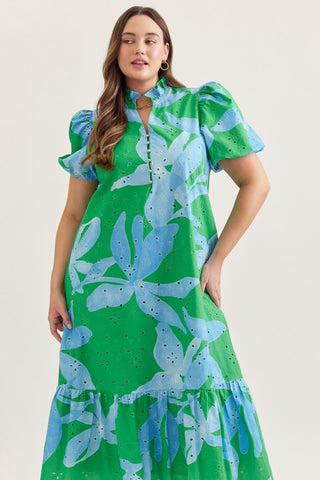 Woman wearing a green and blue floral dress on a plain background